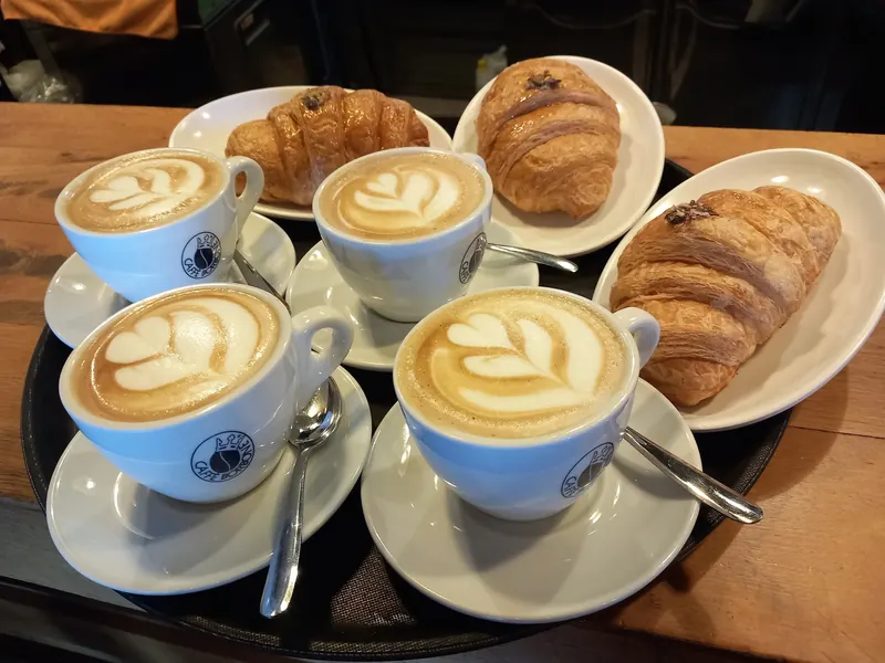 Four cappuccinos with latte art and croissants on a tray