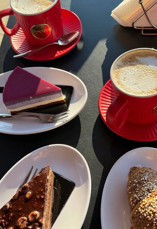 Cake slices and cappuccinos in red cups