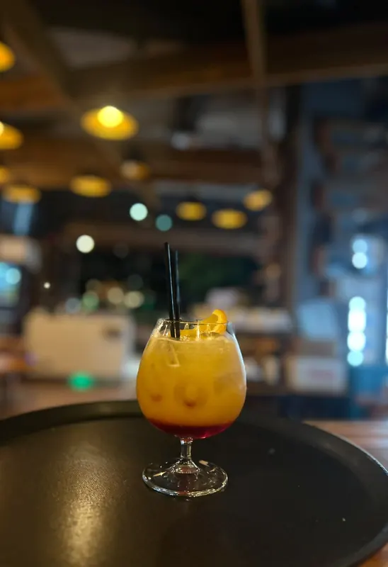 An iced orange drink on a black tray