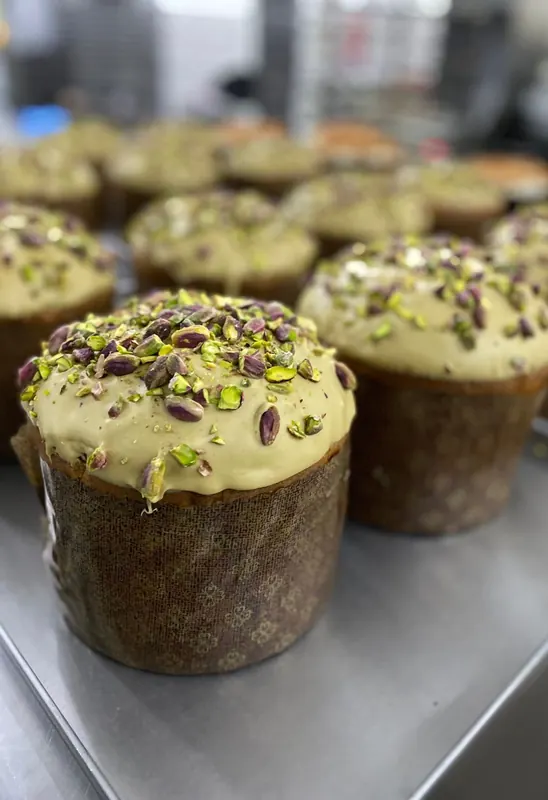 Small panettoni topped with pistachio cream and chopped pistachios